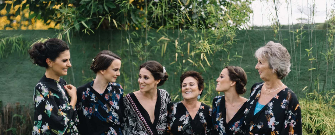 6 women standing in a line laughing and embracing. wearing black kimonos