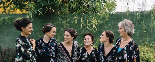 6 women standing in a line laughing and embracing. wearing black kimonos