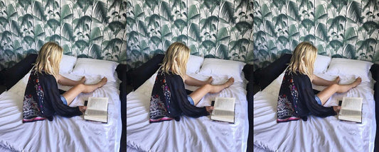 woman wearing kimono robe reading book. tropical wallpaper behind.  