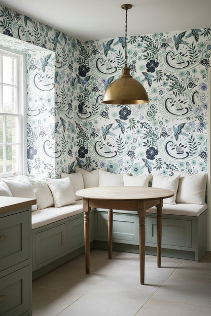 A kitchen seating area that is lined in the hand‑drawn Holland Street “Park Life” wallpaper, featuring birds, boats, and flowers in dark blue, white and pale blue tones, designed in Britain.
